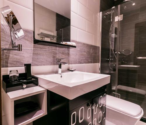 a bathroom with a white sink and a toilet at Oak Plaza Suites in Kumasi