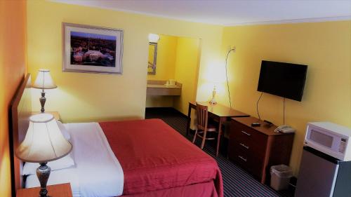 a hotel room with a bed and a flat screen tv at Roadway Inn Troy in Troy
