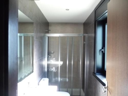 a bathroom with a shower and a sink and a mirror at PENSIÓN RESTAURANTE "O RETIRO " in Arzúa