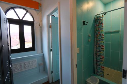 a bathroom with green tiles and a window and a shower at Magnolia Inn in Panama City