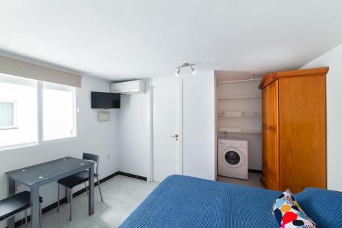 Un dormitorio con una cama y una mesa y una lavadora. en Coqueto estudio, en Cádiz