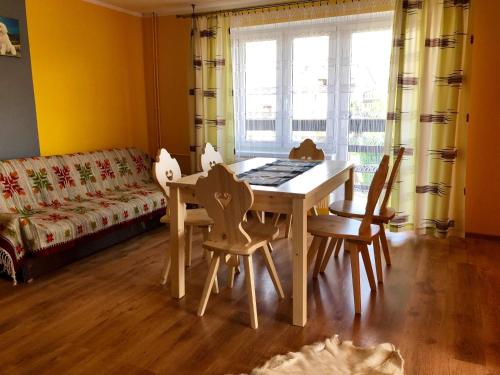 a dining room with a table and chairs and a couch at Apartamenty "U Bańki" in Kluszkowce