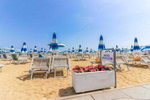 a beach with chairs and umbrellas and a sign at Hotel Jesulum in Lido di Jesolo