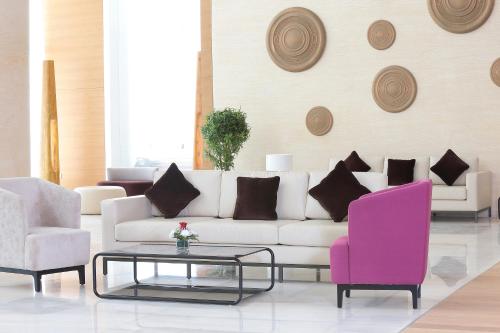 a living room with a white couch and two pink chairs at Novotel Jazan in Jazan