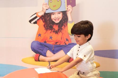 a young boy sitting next to a girl holding up a sign at Novotel Jazan in Jazan