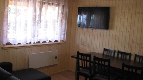 a dining room with a table and chairs and a window at Domki Letniskowe ARKON in Strykowo