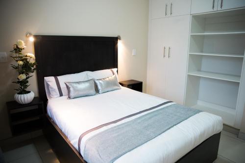a bedroom with a large white bed with two pillows at The Living Collective Apartments in Pietermaritzburg