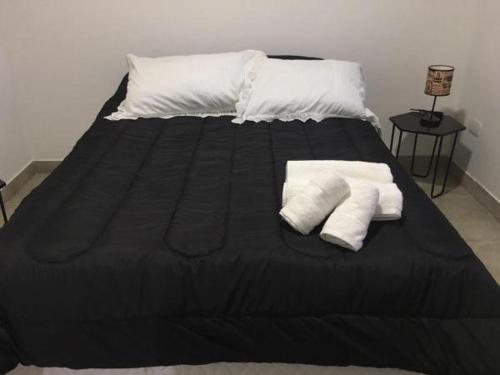 Una cama negra con dos toallas blancas. en Studio Escobar en Belén de Escobar