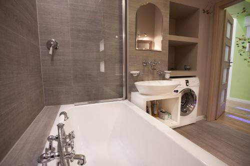 a bathroom with a tub and a sink and a washing machine at Warsaw Concierge Traveller's Nest Wspólna in Warsaw