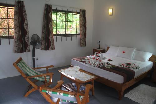 a bedroom with a bed and a table and a chair at Daniella's Bungalows in Bel Ombre