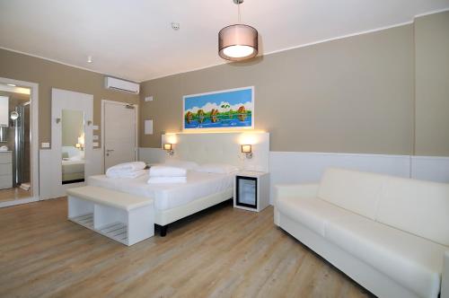 a white room with two beds and a couch at Marina Palace Hotel 4 stelle S in Caorle