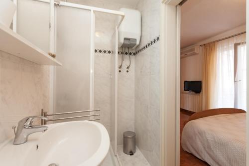 a white bathroom with a sink and a shower at Apartments Alice in Rovinj