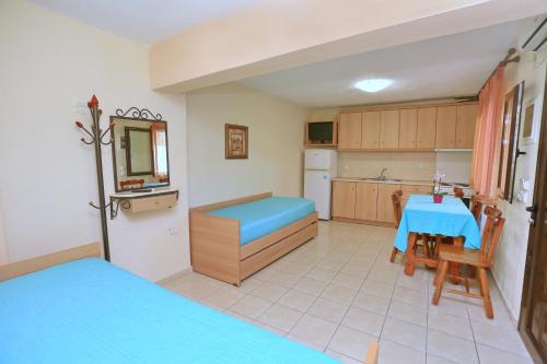 a room with a kitchen and a table with a blue bed at Katerina Apartments in Pefkohori