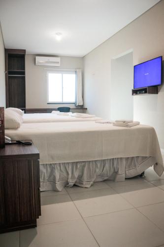 a large bed in a room with a tv at Ello Hotel in Iguatu