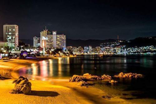 a view of a beach at night with a city at Costa Miramar in Acapulco