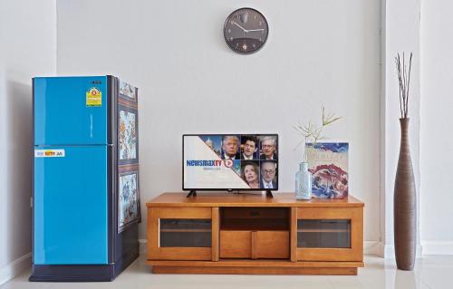 a blue refrigerator sitting next to a table with a clock at Chez Bure - Bure Homestay in Kanchanaburi