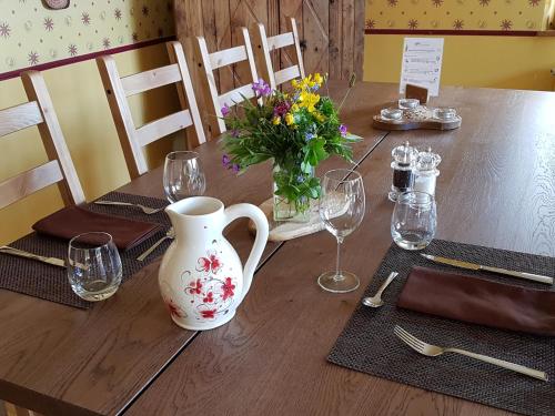a wooden table with a vase and flowers on it at La Girandole Chambre d'hôtes et Location d'appartement in Arvieux