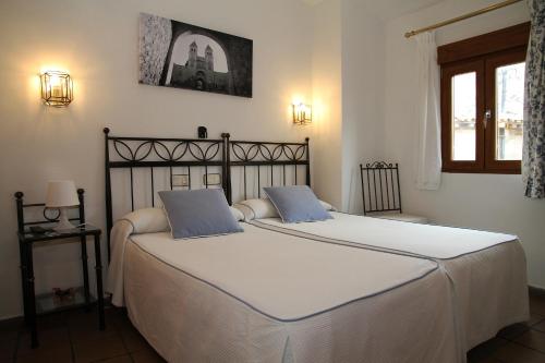 a bedroom with two beds with white sheets and blue pillows at Hostal la posada de Zocodover in Toledo