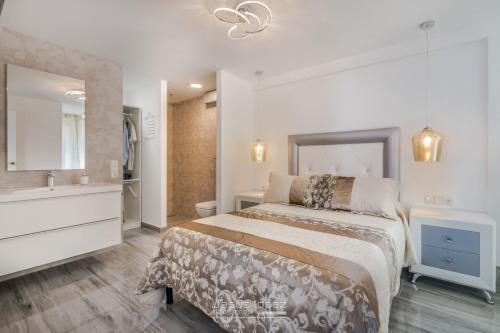 a bedroom with a large bed and a sink at Junto al mar in Torre del Mar