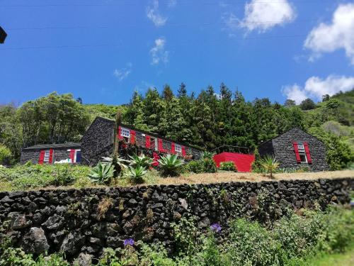 a house with red windows and a stone wall at Casas de Incensos - TER -TA in Pontas Negras