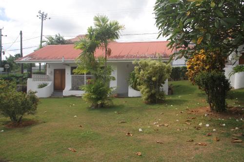 a white house with trees in front of it at Daniella's Bungalows in Bel Ombre