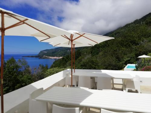 una mesa y sillas blancas con vistas al océano en Casas de Incensos - TER -TA en Pontas Negras