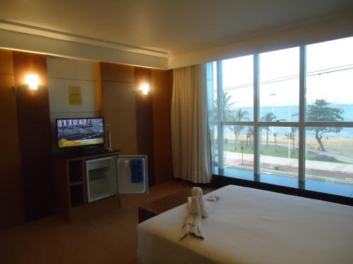 Hotel Minuano في فيتوريا: غرفة فندقية بسرير ونافذة كبيرة