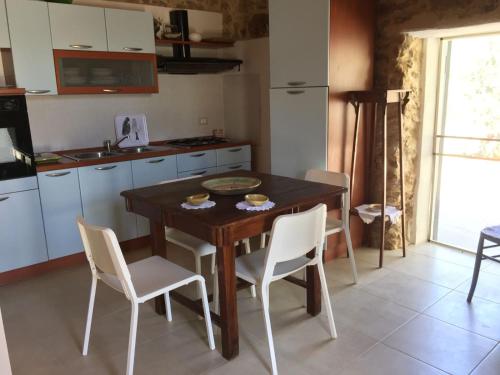 a kitchen with a wooden table and white chairs at Casa le Gebbie in Marzamemi