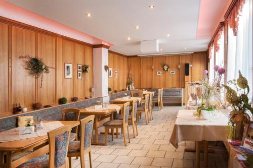 ザールフェルトにあるHotel Weltrichの木製の壁とテーブルと椅子が備わるレストラン