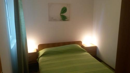 een kleine slaapkamer met een bed en 2 verlichting bij Apartmani Božić-Omišalj in Omišalj