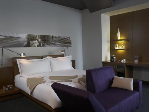 a bedroom with a bed and a purple chair at Hotel Le Germain Calgary in Calgary