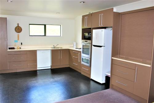 a kitchen with white appliances and brown cabinets at Cozy Home in Rotorua