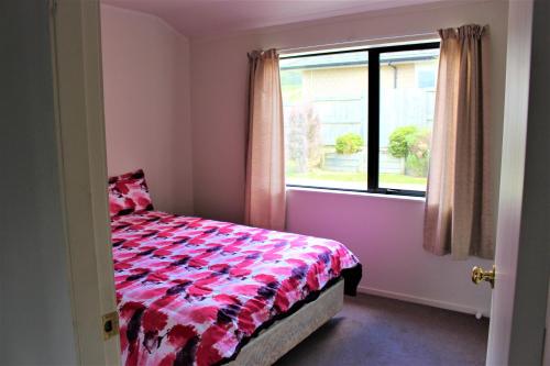 a bedroom with a bed and a window at Cozy Home in Rotorua