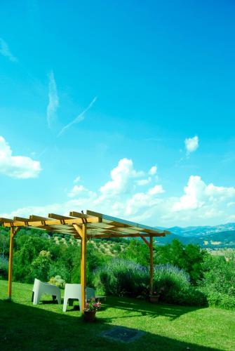 a wooden pergola with two tables and chairs on a lawn at Vigna del Poggio in Anghiari