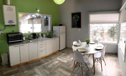 a kitchen with white cabinets and a table and chairs at Esquel Apart in Esquel