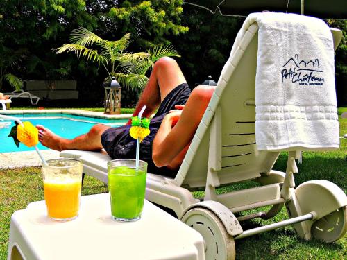 a man sitting in a chair next to a table with two drinks at Petit Chateau Hotel Boutique in Punta del Este