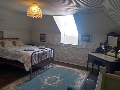 a bedroom with a bed and a window and a chandelier at Tanilba House in Lemon Tree Passage