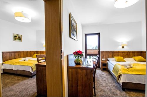 una habitación de hotel con 2 camas y una mesa con flores en Dworek Nad Białką, en Czarna Góra