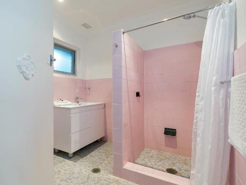 a pink bathroom with a shower and a sink at Dutchies Motel Nelson Bay & Dutchmans Beach Apartments in Nelson Bay