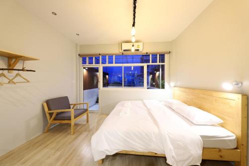 a bedroom with a bed and a chair and a window at Ekanake hostel in Bangkok
