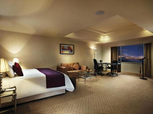 a hotel room with a bed a couch and a desk at Resorts World Genting - Genting Grand in Genting Highlands