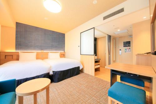 姫路市にあるリッチモンドホテル姫路のベッドとデスクが備わるホテルルームです。