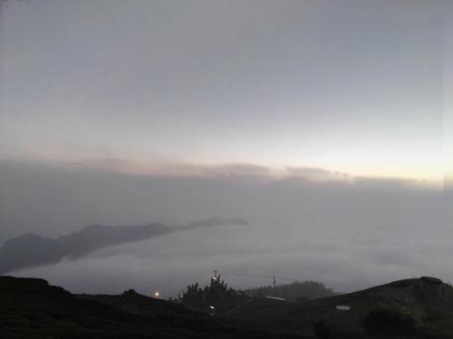a view of a foggy valley with the sun rising above the clouds at Qun Feng Hotel in Fenchihu