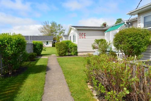 a yard with a white house and bushes at Trailsman Lodge in Baddeck