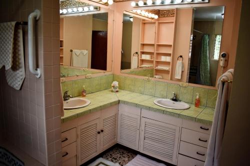 a bathroom with two sinks and two mirrors at Cariari Bed & Breakfast in San José