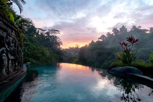 a river in the middle of a forest at sunset at Bidadari Private Villas & Retreat in Ubud