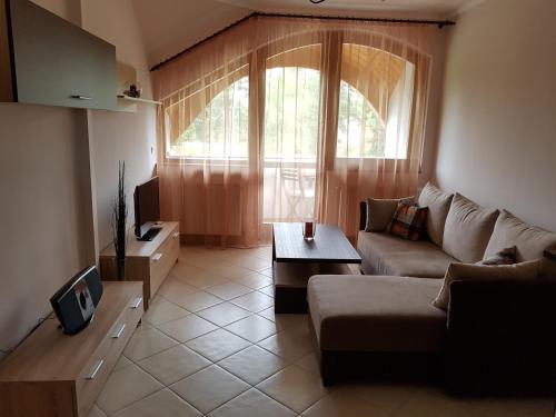 a living room with a couch and a tv at Napsugár Apartman in Balatonlelle