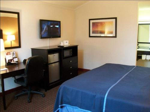 a hotel room with a bed and a desk with a computer at Americas Best Value Inn Romulus/Detroit Airport in Romulus