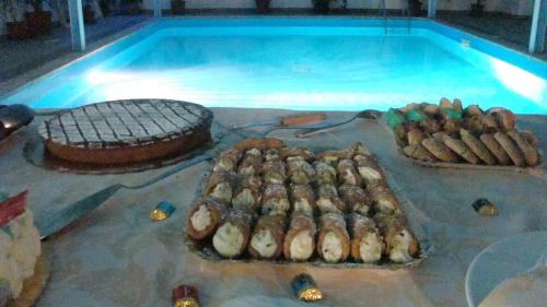 a bunch of food on a table next to a swimming pool at Hotel Kennedy in SantʼAlessio Siculo