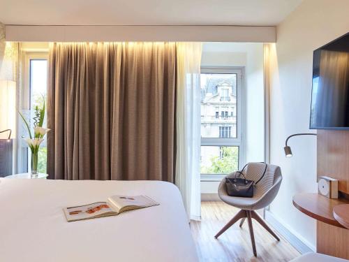 a hotel room with a bed and a chair and a window at Mercure Paris Arc de Triomphe Etoile in Paris